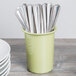 A sage green Cal-Mil flatware cylinder holding silverware.