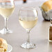 A table with two Acopa all-purpose wine glasses filled with white wine next to a plate of bread.