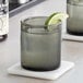 Two Acopa Pangea old fashioned glasses with whiskey and lime wedges on a marble counter.
