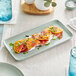 A rectangular Harbor Blue matte porcelain platter with tomatoes on a table.