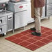 A person standing on a red Choice rubber anti-fatigue floor mat.