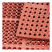 A close-up of a red rubber anti-fatigue floor mat with holes in it.