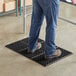A man standing on a Choice black anti-fatigue floor mat.