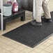 A person standing on a Choice black rubber anti-fatigue floor mat.