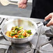 A chef uses a Vollrath stainless steel saucier pan to cook vegetables.