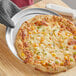 A pizza with cheese and vegetables on a Choice 10" Aluminum Wide Rim Pizza Pan.