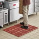 A man standing on a red Choice anti-fatigue floor mat.