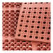 A close up of a red rubber Choice anti-fatigue floor mat with a straight edge and holes in the surface.