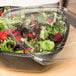 A Sabert clear plastic lid on a salad in a plastic container.