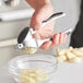 A person using a Choice chrome garlic press to squeeze garlic into a bowl.
