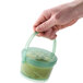 A hand holding a jade green GET soup container handle.