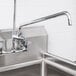A stainless steel Equip by T&amp;S 12" swing nozzle on a sink with a faucet.