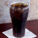 A GET clear plastic soda glass filled with dark liquid and ice on a table.