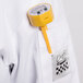 A yellow Taylor digital pocket probe thermometer clipped to a white shirt pocket.