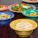 A variety of GET Diamond Mardi Gras melamine bowls filled with colorful foods on a table.