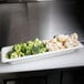 A white Cambro food pan with broccoli and cauliflower on a counter.