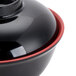 A black melamine bowl with a red rim.