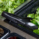 A black plastic Cambro tongs in a container of spinach.