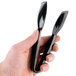 A hand holding a pair of black tongs.
