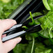 A person using Cambro black plastic tongs to serve spinach from a salad bar.