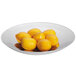 A Vollrath stainless steel round platter filled with yellow lemons.