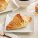 A plate with a Bridor Ready to Bake Mini Straight Perfect Croissant and a cup of coffee.
