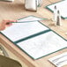 A hand opening a green Choice trifold menu on a table.