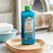 A blue bottle of Herbal Essences Bio:Renew Argan Oil Shampoo on a wooden surface.
