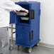 A man putting food in a Cambro navy blue food pan carrier.