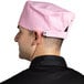 A man wearing a pink Uncommon Chef skull cap in a professional kitchen.