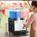 A double-bowl refrigerated beverage dispenser with blue and pink drinks, designed for serving cold beverages.