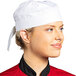 A woman wearing a Uncommon Chef white chef skull cap with ties.