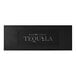 A black rectangular customizable bar mat with white text that says "Tequila" on a table in a bar.