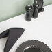 A white table with a white Intedge vinyl table cover, set with a black napkin and salt and pepper shakers.