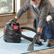 A man using a Shop-Vac wet/dry vacuum to clean a carpet.