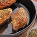A skillet with chicken breasts seasoned with Regal Fancy Oregano Leaves.
