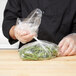 A person in a chef's uniform using an LK Packaging plastic bag to hold green beans.