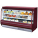 A red Turbo Air curved glass refrigerated deli case with food on shelves.