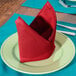 A folded red Intedge cloth napkin on a plate.