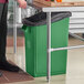 A person standing next to a Lavex green rectangular recycling bin.