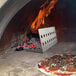 A meat and mushroom pizza cooking in a Pinnacolo wood-fired oven with flames.