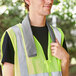 A man wearing a yellow safety vest using an Ergodyne gray evaporative cooling towel.