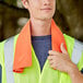A man wearing a safety vest holding an orange Ergodyne evaporative cooling towel.