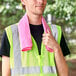 A man wearing a safety vest holding a pink Ergodyne cooling towel.