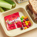 A tray of food with a packet of Skittles on it.