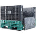 A black and green Orbis collapsible container on a plastic pallet with the doors open.