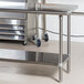 An Advance Tabco stainless steel work table with an undershelf on wheels.