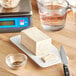 A block of Fleischmann's Fresh Compressed Yeast on a plate next to a knife and measuring cup.