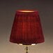A Sterno wine cloth lamp shade on a gold base with a red lamp shade.