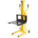 A yellow Vestil portable hand winch lifter with a black table.